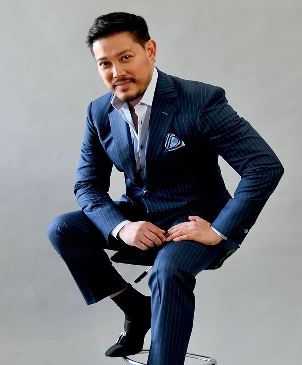 Man in a striped suit sitting confidently.
